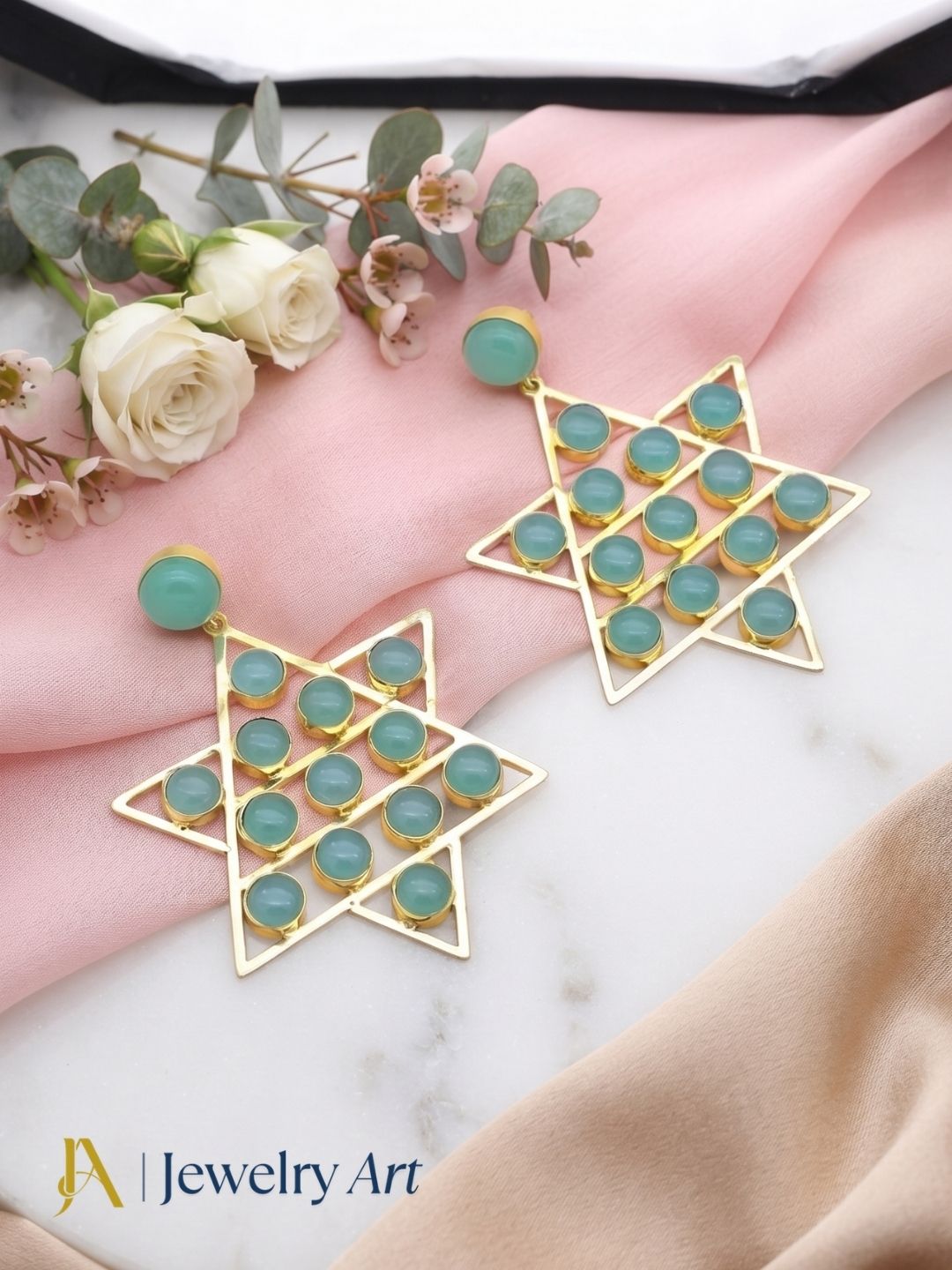 Designer Chalcedony earrings displayed with elegant decorative props
