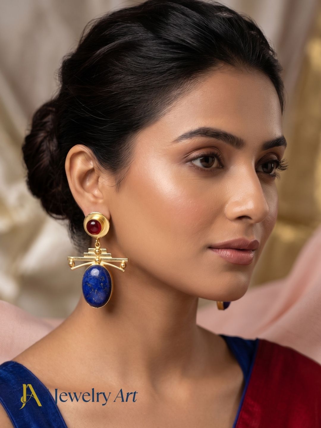 Woman wearing designer gold plated lapis and red onyx gemstone earrings.

