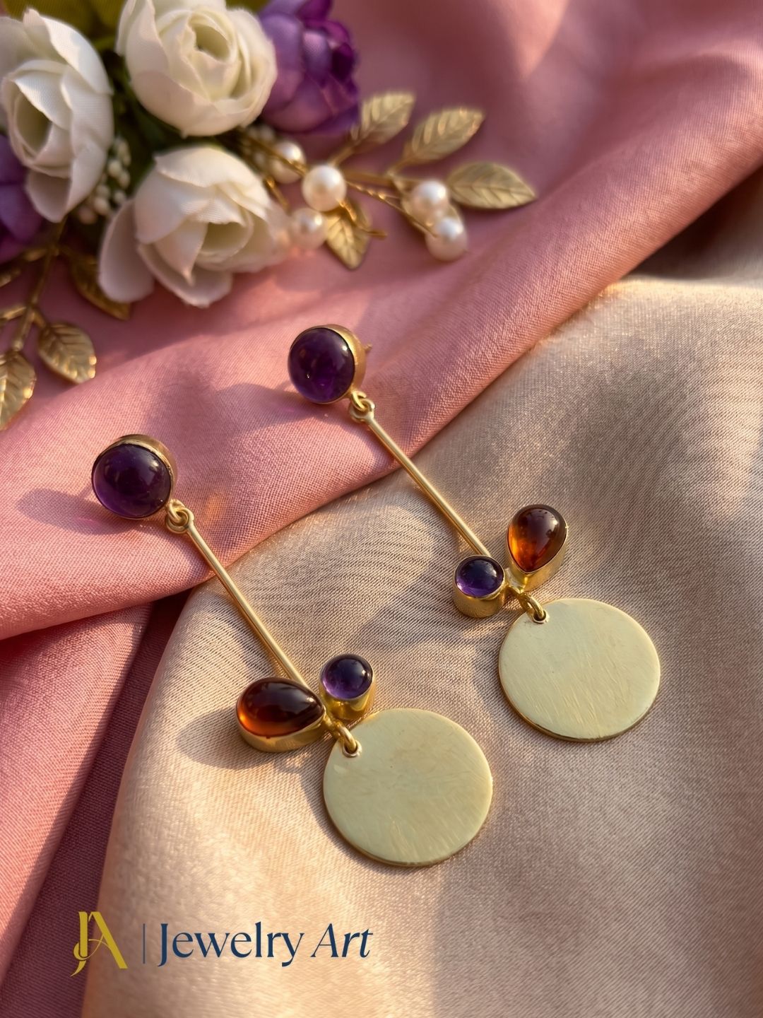 Gold plated amethyst and red onyx earrings styled in an elegant decorative jewelry setup
