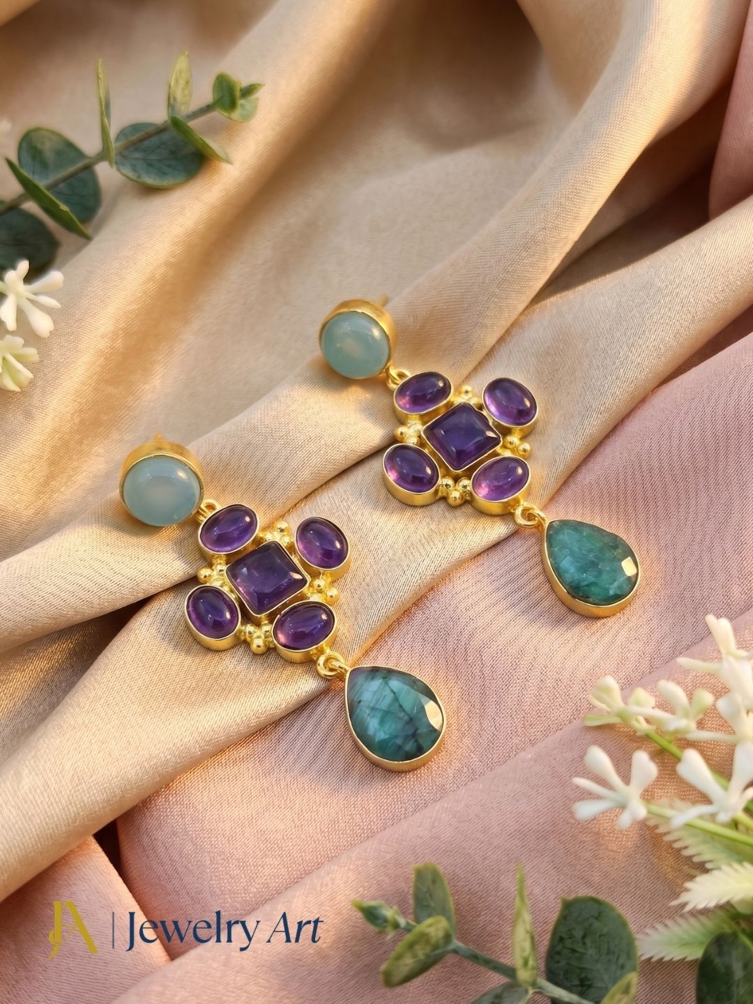 Multi gemstone earrings displayed with luxury decorative props and soft lighting
