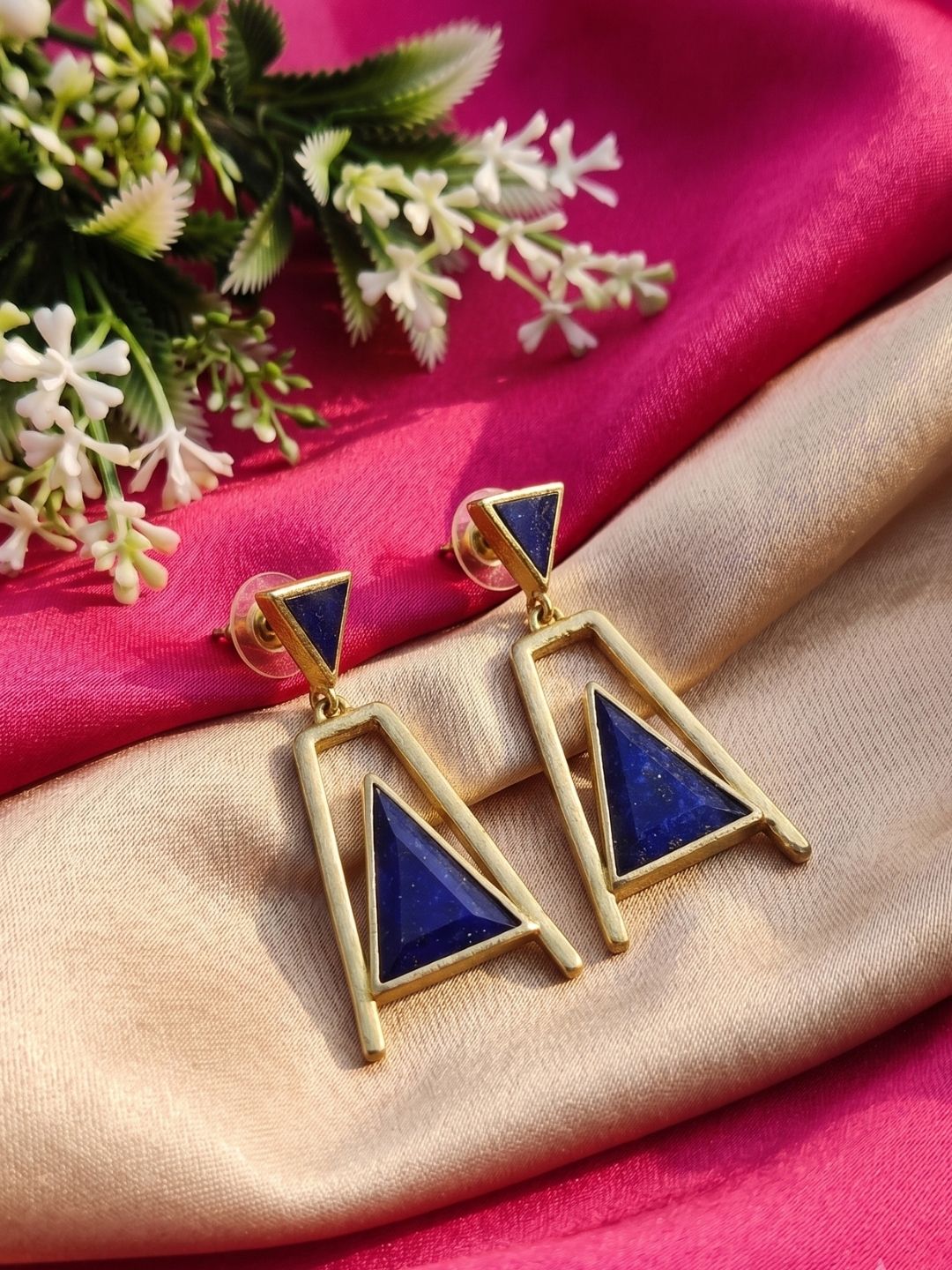 Handmade lapis gemstone dangle earrings displayed with decorative props

