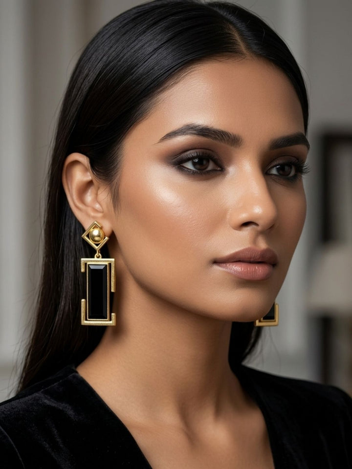 Woman wearing gold plated black onyx geometric drop earrings, elegant contemporary designer jewelry
