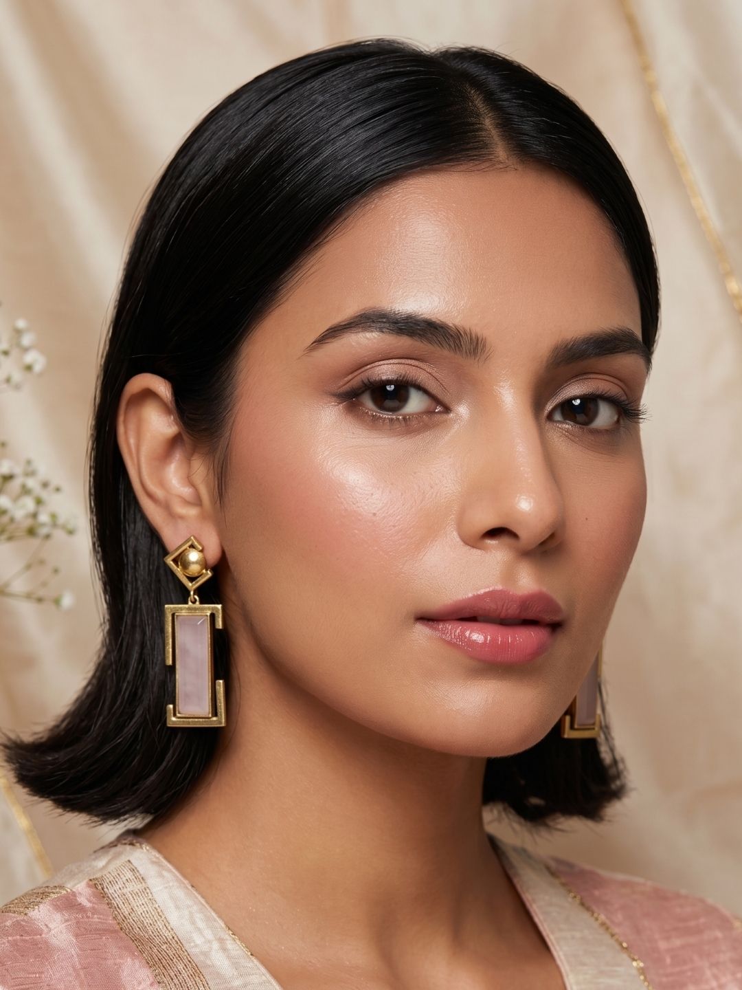 Model wearing pair of handmade gold plated rose quartz geometric drop earrings 
