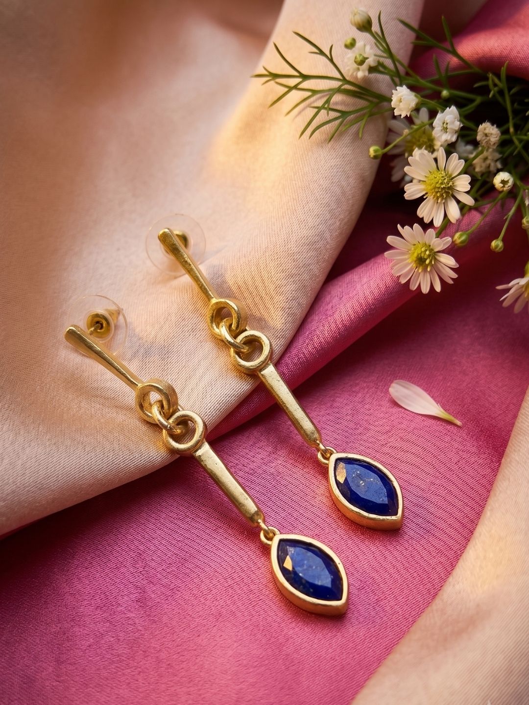 Gold plated long dangle earrings with natural lapis stones isolated on a white background.
