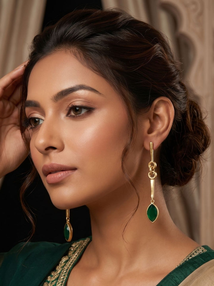Woman wearing designer green onyx stone long dangle gold plated earrings 
