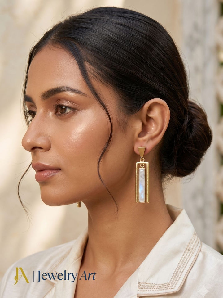 Woman styling geometric white rainbow gemstone drop earrings with a sophisticated modern outfit.
