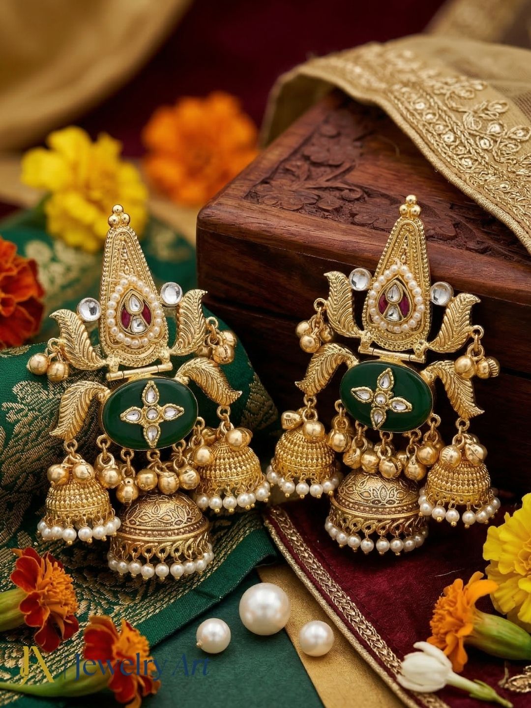 Pair of gold and green traditional earrings with pearls on a decorative background.