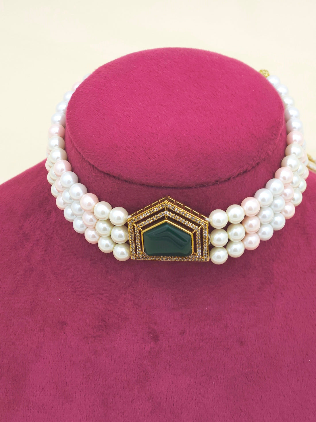 Zoomed-in shot of antique gold choker highlighting textured gold finish, green stone, and shimmering AD crystals with pearls
