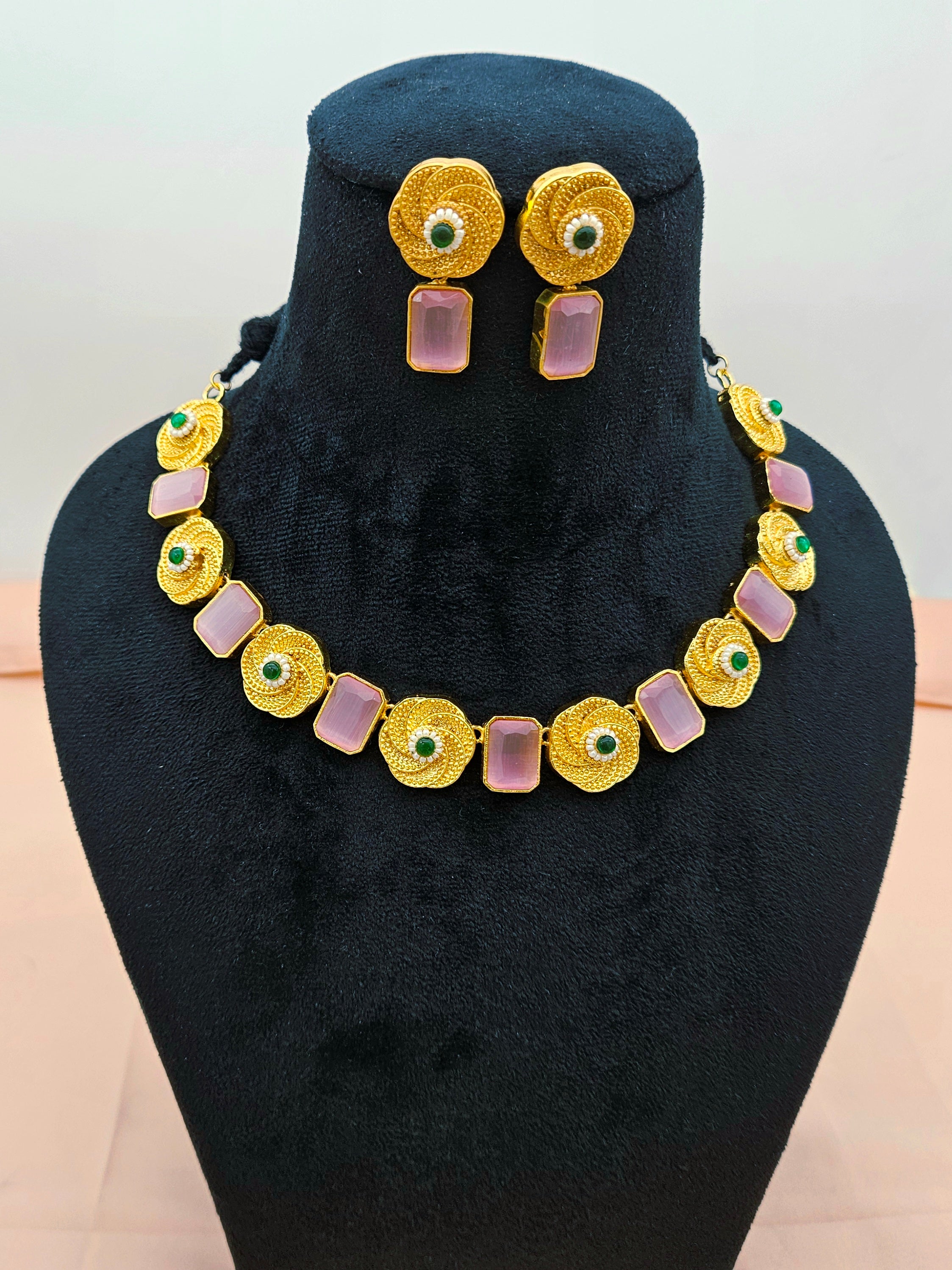 Beautiful antique gold plated jewelry set with pink Monalisa stones displayed on a necklace display stand.