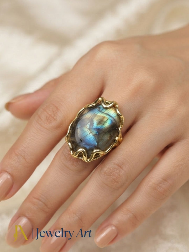 Close-up of a woman's hand wearing a handcrafted Labradorite gemstone gold plated ring highlighting artistic craftsmanship and timeless elegance.
