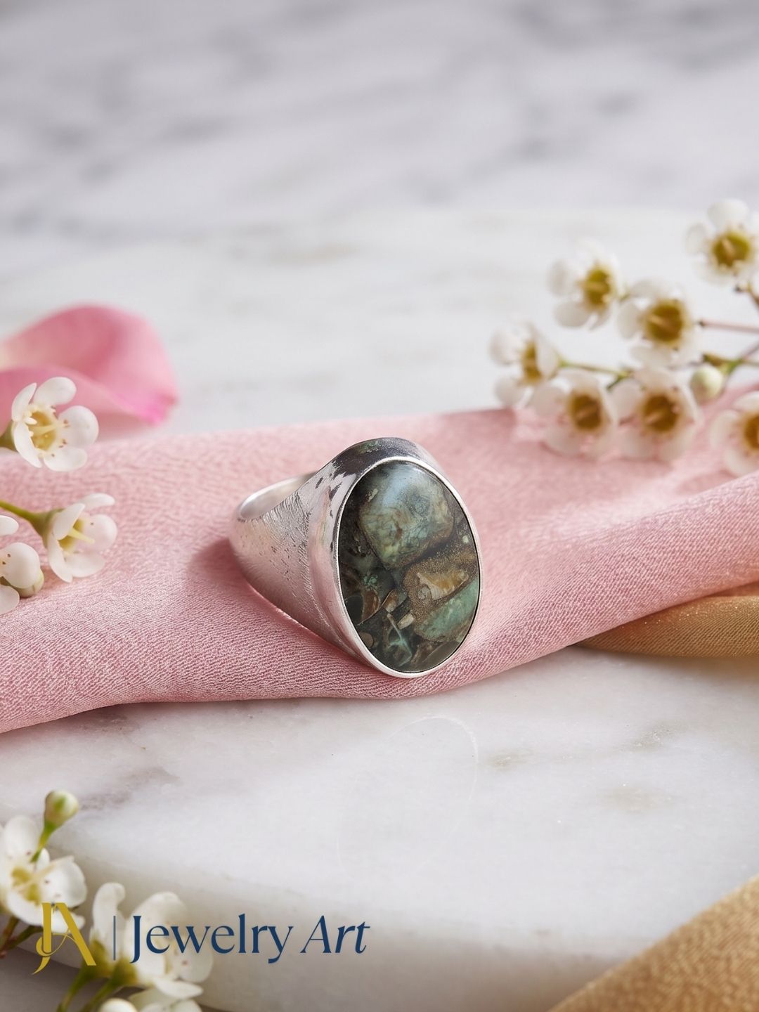 Creative jewelry styling showcasing a silver plated GS Copper Chrysocola gemstone ring with elegant decorative elements.
