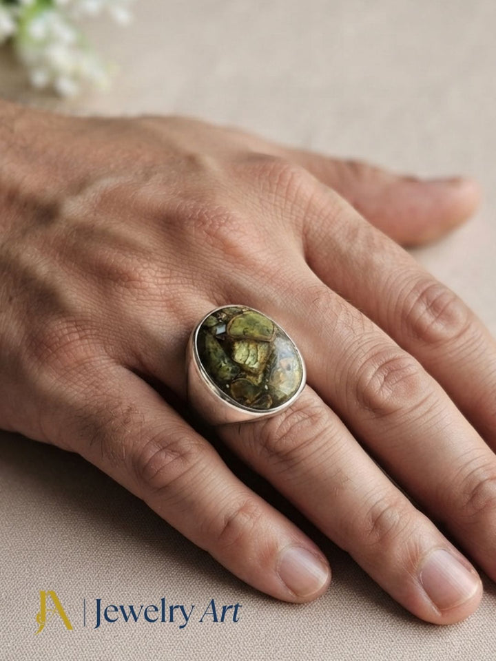 Close-up of a man's hand wearing a natural Copper Chrysocola gemstone silver plated GS ring showcasing artisan craftsmanship and elegant design.
