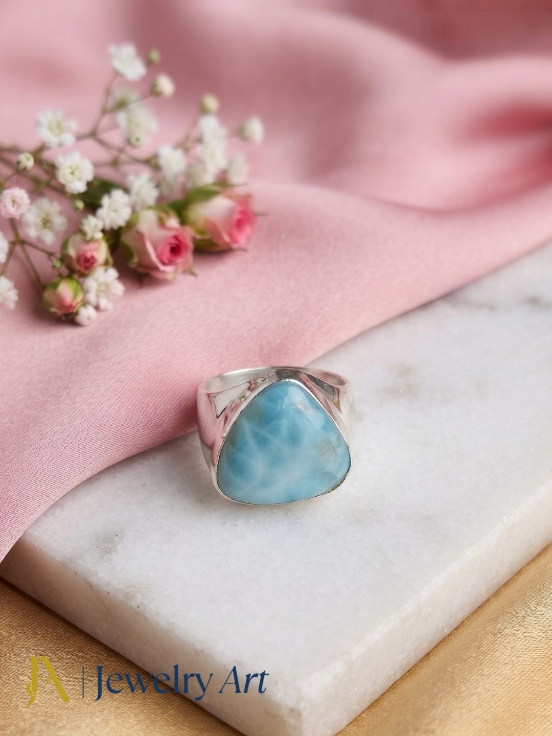 Natural Larimar gemstone ring in silver plated GS displayed in a refined decorative jewelry arrangement.
