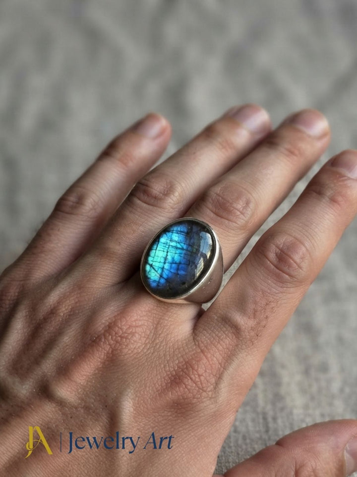Stylish man wearing a handcrafted Labradorite stone ring in silver plated GS for a premium men's fashion jewelry photoshoot.
