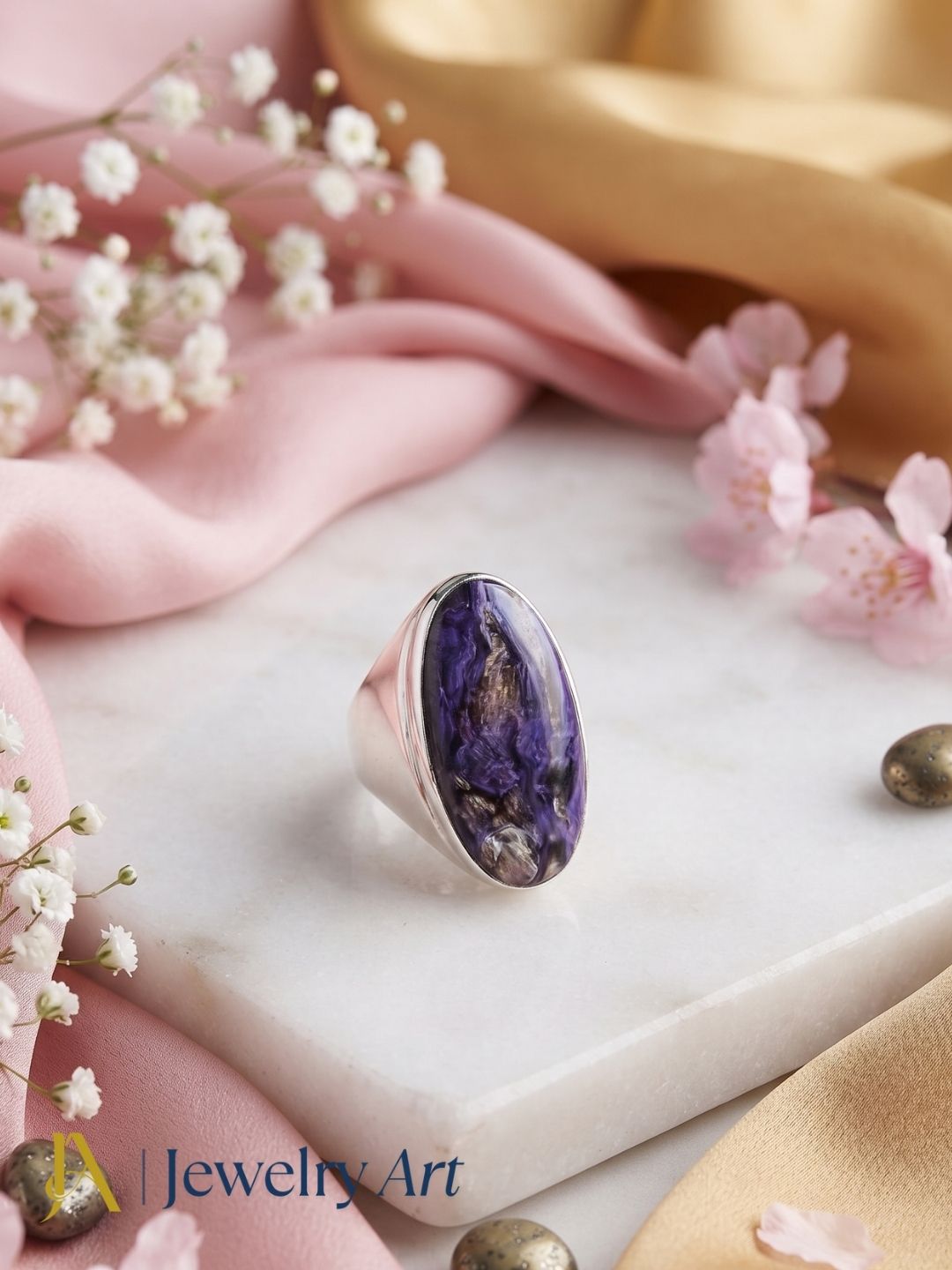 Premium Charoite stone men's designer statement ring styled with elegant decorative props for luxury product photography.
