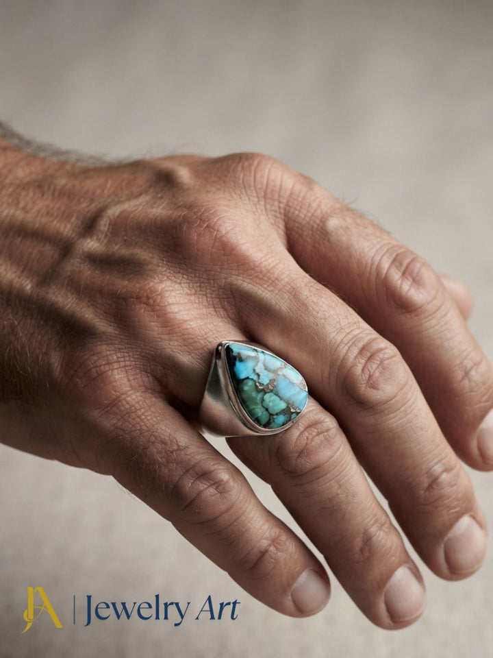 Close-up of a man's hand wearing a natural Copper Turquoise gemstone Silver Overlay GS ring showcasing artisan craftsmanship and elegant design.
