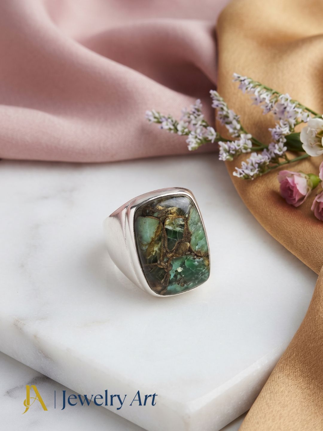 Creative jewelry styling showcasing a silver plated GS Copper Chrysocola gemstone ring with elegant decorative elements.
