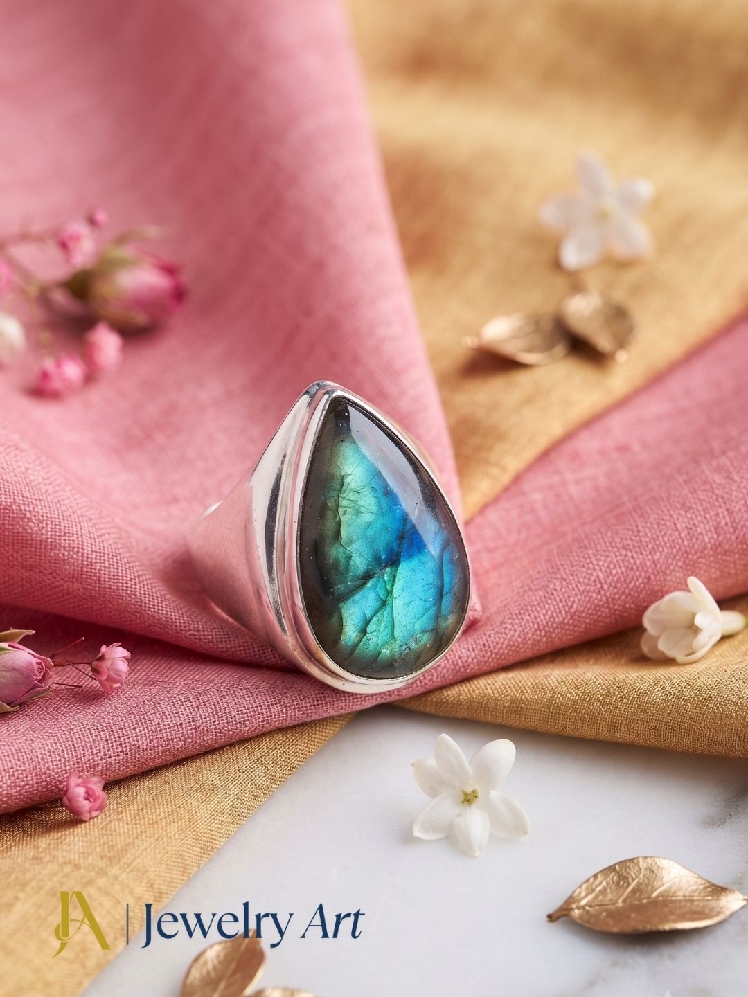 Elegant decorative arrangement highlighting a natural Labradorite gemstone ring with a silver plated GS finish.
