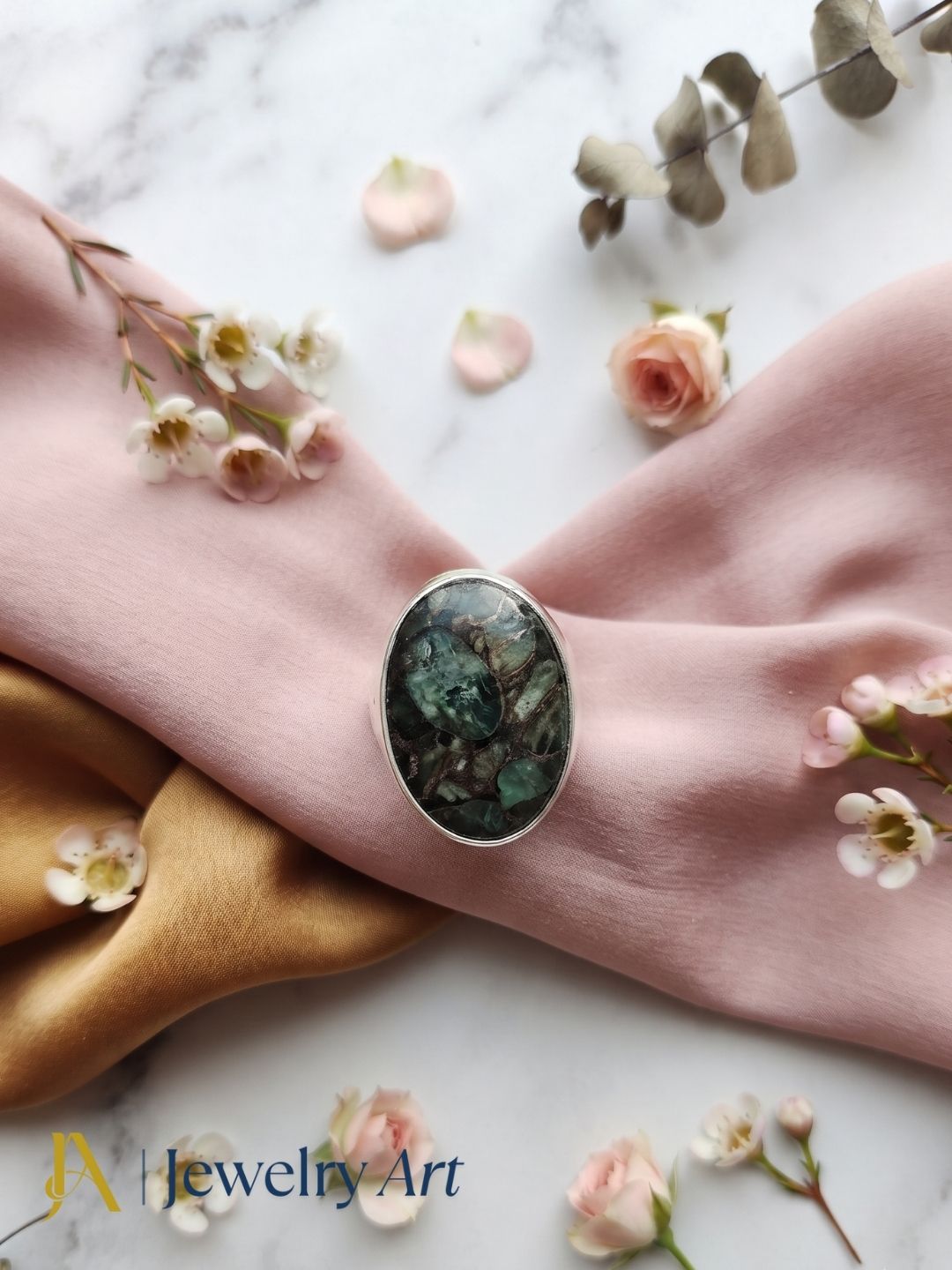 Editorial-style decorative photography featuring a handcrafted Copper Chrysocola gemstone men's designer ring.
